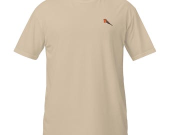May include: A beige short-sleeve t-shirt with a crew neckline. The shirt features a small embroidered robin bird on the upper left chest area. The interior neck label displays the text "Ares & Thread" in a simple, dark font on a light background.