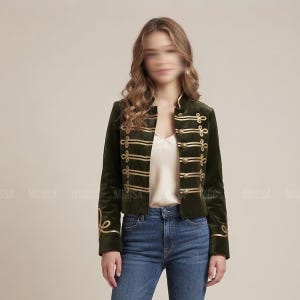 以下が含まれることがあります： ハイカラー、長袖、フロントにゴールドの編み込みコードのディテールをあしらったダークオリーブグリーンのベルベットジャケット。ゴールドカラーのボタンと袖口の装飾的なゴールドの刺繍が特徴で、白いトップスの上に着用されています。