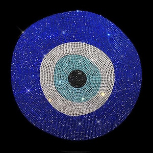 Könnte beinhalten: Ein kreisförmiger Wandbehang mit einem Nazar-Auge-Motiv, das aus zahlreichen kleinen, reflektierenden Kristallen besteht. Das Design zeigt eine schwarze Pupille, eine hellblaue Iris, einen weißen Ring und ein großes, tiefblaues Außenfeld.