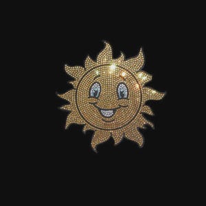 May include: A sun-shaped iron-on patch or transfer design composed of numerous small, reflective gold-toned rhinestones. The sun features a smiling face with white crystal eyes and a white crystal mouth, set against a solid black background.