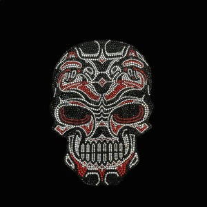 May include: A skull-shaped patch decorated with a dense arrangement of small rhinestones. The design features intricate patterns in black, white, and red, creating a detailed visual texture across the entire surface of the skull motif.