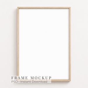 May include: A vertical rectangular picture frame with a light-toned natural wood finish and a plain white center. The frame features a simple, clean-lined border design. The text "FRAME MOCKUP" and "Instant Download" is visible at the bottom.