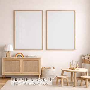 May include: Two vertical rectangular frames with light wood borders mounted on a wall above a light wood cabinet with cane doors. A small lamp, a rainbow decor piece, and books sit on the cabinet. A small round table and two stools are nearby.