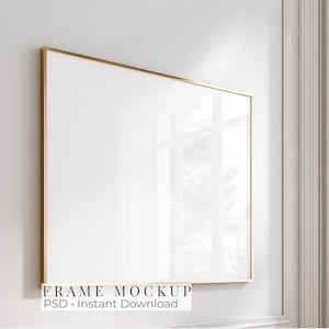 May include: A rectangular picture frame with a thin gold metallic border and a blank white center. The frame is displayed against a plain white wall. The text "FRAME MOCKUP PSD Instant Download" is printed in black at the bottom of the image.