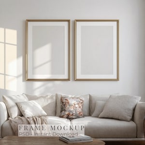 May include: Two gold framed rectangular mockups hang above a beige sofa with several pillows. A patterned pillow sits in the center. The text "FRAME MOCKUP PSD - Instant Download" is at the bottom.