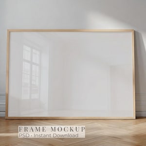 May include: A large, rectangular wooden frame mockup with a white interior. The frame is set against a white wall and rests on a wooden floor. The text "FRAME MOCKUP PSD • INSTANT DOWNLOAD" is at the bottom.