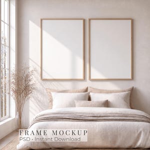 Op de afbeelding: Twee verticale rechthoekige houten lijsten met witte passe-partouts hangen aan een lichtbeige muur boven een bed met neutraalkleurig beddengoed. De tekst "FRAME MOCKUP PSD Instant Download" staat in het midden in zwarte letters.