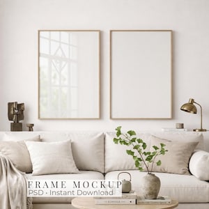 Könnte beinhalten: Zwei vertikale rechteckige Rahmen mit dünnen hellen Holzrändern, die an einer Wand über einem beigen Sofa hängen. Die Rahmen sind leer mit weißem Hintergrund. Der Text "FRAME MOCKUP PSD - Instant Download" ist mittig eingeblendet.
