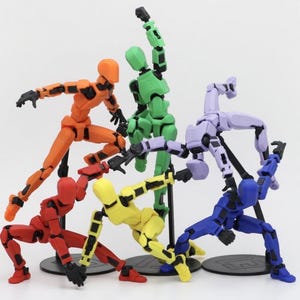 May include: A collection of six articulated action figures in various colors: orange, green, purple, blue, red, and yellow. Each figure is posed dynamically, with black joints and stands on a black base. The figures are designed to be posed.