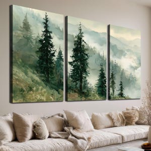 May include: A triptych wall art set featuring a watercolour landscape of dark green pine trees on a misty, fog-covered mountain slope. The three vertical panels display a continuous forest scene with soft, muted tones of sage, cream, and forest green.