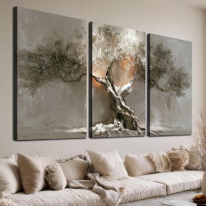 Può includere: Un set di tre pannelli artistici da parete con un dipinto materico di un ulivo dal tronco nodoso e foglie color argento su uno sfondo beige neutro. L'opera d'arte mostra una luce calda e luminosa dietro la chioma dell'albero.