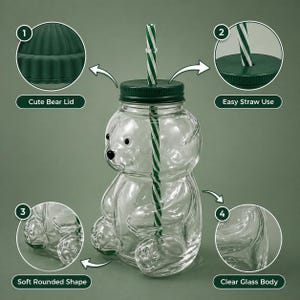 May include: A clear glass bear-shaped drinking jar with a green lid and a green and white striped straw. The jar has a soft, rounded shape and is designed for easy straw use. The lid is labeled "Cute Bear Lid".