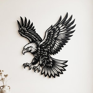 May include: A black wall-mounted eagle sculpture featuring a detailed silhouette of the bird in flight with wings spread wide, sharp talons extended forward, and intricate feather patterns throughout the design, creating a bold visual statement.