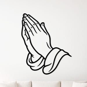 May include: Black and white wall art depicting hands in prayer. The hands are clasped together, with fingers interlaced. The artwork is a minimalist design, suitable for various interior styles. The hands are outlined with a thick black line.