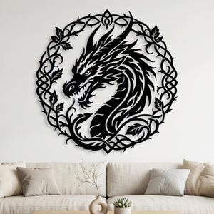 May include: A circular black wall art piece featuring a detailed dragon head profile surrounded by an intricate frame of intertwined vines and leaves. The dragon is depicted with sharp features, scales, and an open mouth, all rendered in a flat silhouette.