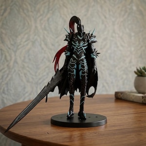 May include: A detailed figurine of a warrior in dark armor with teal accents and a long, black sword. The figure has a black cape and red hair. It stands on a black circular base, showcasing intricate design and craftsmanship.