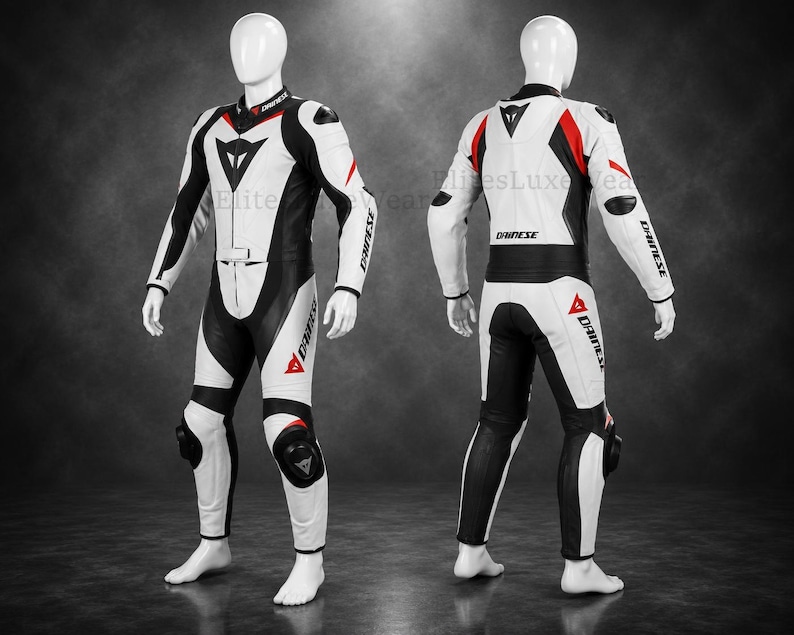 May include: A white and black motorcycle racing suit with red detailing. The suit has a sleek design, with the brand name "DAINESE" printed on the sleeves and legs. The suit is displayed on a mannequin.