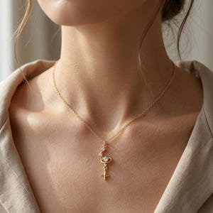 May include: A delicate gold necklace featuring a celestial design. The pendant includes a crescent moon shape with embedded clear crystals, a star, and a small cross. The necklace is worn on a person.