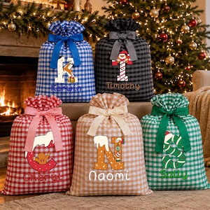 Pode incluir: Cinco sacos de presente de tecido com padrões xadrez vichy em azul, preto, vermelho, bege e verde. Cada saco apresenta uma letra grande com gráficos de Natal e um nome personalizado: Kerwin, Timothy, Cheryl, Naomi e Sally. Cada saco tem um laço.
