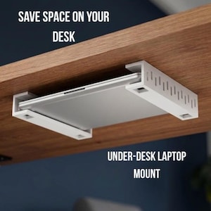 May include: White under-desk laptop mount holding a silver laptop, attached to a wooden desk. The image includes the text "SAVE SPACE ON YOUR DESK" and "UNDER-DESK LAPTOP MOUNT".