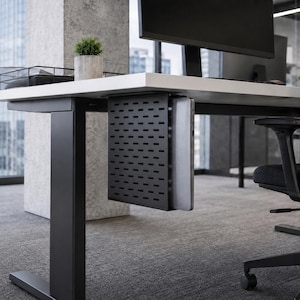 May include: A modern black computer desk with a built-in CPU holder. The desk has a white tabletop, black legs, and a black perforated metal CPU enclosure. A computer monitor and a small potted plant are visible on the desk.