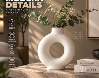 May include: A white, donut-shaped ceramic vase with a textured finish, holding green eucalyptus branches and small white flowers. The image includes text: MODERN DETAILS, A MORE BEAUTIFUL EVERYDAY, TIMELESS DESIGN, PREMIUM MATERIALS, FITS ANY SPACE, BEAUTY THAT LASTS, SMALL DETAILS A BIGGER HOME, NATURE SHAPES HAPPIER SPACES, LIVE BEAUTIFULLY.