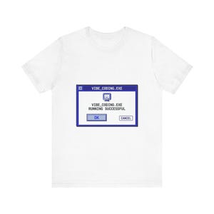 Peut inclure: T-shirt blanc avec un motif bleu imitant une fenêtre contextuelle d'ordinateur. Le texte indique "VIBE_CODING.EXE RUNNING SUCCESSFUL" avec les boutons "OK" et "CANCEL". Le motif comprend une icône d'ordinateur souriante.