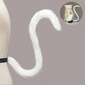 May include: A fluffy white cat tail, curved in a gentle S-shape, attached to a black belt. The tail is made of soft, faux fur. A smaller image shows a matching set with cat ears.