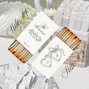 May include: Two open matchboxes with orange-tipped matches. One box features a swan design and the text "The Houstons" and "06.25.27". The other box has two heart-shaped lockets with the letters "A" and "H".
