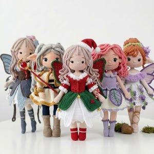 May include: A collection of six handmade crochet fairy dolls. Each doll has unique features, including different colored hair, wings, and outfits. One doll wears a Santa hat and a red and green dress. The dolls are standing in a row.