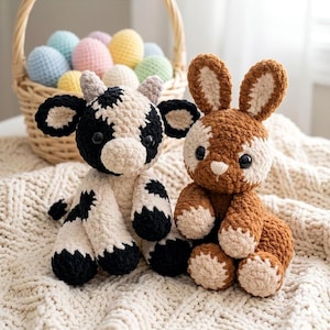 Puede incluir: Dos animales de peluche hechos a mano con ganchillo: una vaca negra y blanca y un conejo marrón y blanco. La vaca tiene manchas negras y el conejo tiene orejas largas. Una cesta de huevos de ganchillo coloridos se encuentra en el fondo, sugiriendo un tema de Pascua.