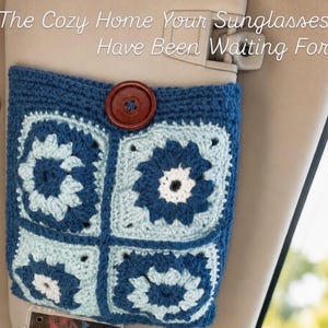 May include: A blue and light blue crocheted pouch featuring four square floral motifs and a large brown button closure. The text "The Cozy Home Your Sunglasses Have Been Waiting For" is printed in white across the top of the image.