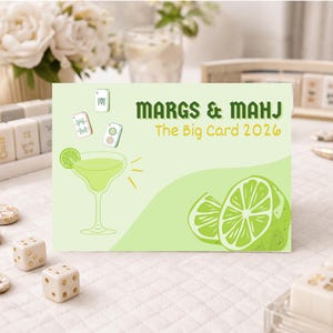 May include: A light green card with the text "MARGS & MAHJ The Big Card 2026" features a lime margarita illustration and lime slices. Mahjong tiles, dice, and decorative pieces surround the card, suggesting a game-themed product.