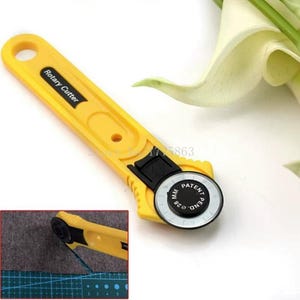 May include: Yellow rotary cutter with a black blade housing and a circular blade. The cutter has the text "Rotary Cutter" printed on the handle. The blade is marked with "28 MM" and "PATENT PEND."