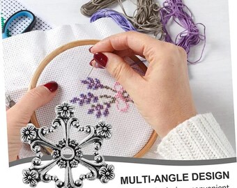 Puede incluir: Un devanador de hilo de metal plateado con forma de copo de nieve de seis puntas y detalles florales en los extremos y el centro. El objeto se muestra junto al texto MULTI-ANGLE DESIGN Multi-angle design, convenient winding.
