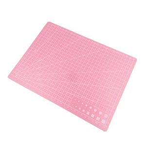 K&ouml;nnte beinhalten: Eine rosa Schneidematte mit einem Rastermuster und Ma&szlig;angaben. Die Matte hat verschiedene Formen und Gr&ouml;&szlig;en f&uuml;r Schneide- und Bastelprojekte. Die Oberfl&auml;che ist f&uuml;r pr&auml;zises Schneiden konzipiert.