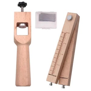 May include: A light-colored wooden leather craft tool set including a vertical punch with a black adjustment knob, a small clear plastic case containing metal blades, and a wooden strap cutter with a printed ruler scale in inches.