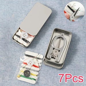 May include: A portable sewing kit in a rectangular metal tin, containing a folding pair of silver scissors, white and black buttons, a gold safety pin, and multiple spools of coloured thread wrapped on white cardstock, labelled as 7 pieces.