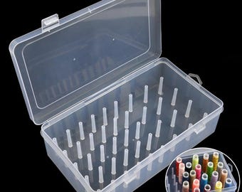 Puede incluir: Una caja organizadora de hilo de plástico transparente con tapa abierta. La caja tiene múltiples clavijas verticales en el interior para sujetar los carretes de hilo. Una imagen más pequeña muestra la caja llena de carretes de hilo de colores.