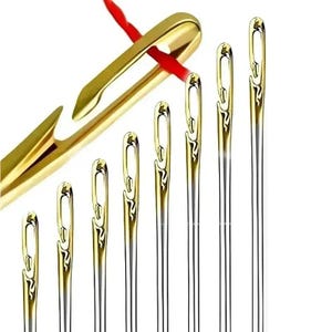 Könnte beinhalten: Ein Set aus acht metallischen Nähnadeln mit goldfarbenen, offenen Ösen, die nach Größe angeordnet sind. Eine Nadel ist schräg abgebildet, wobei ein roter Faden durch die offene Öse verläuft, was das Design der seitlichen Einfädelung verdeutlicht.