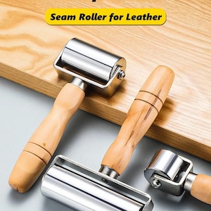 Op de afbeelding: Drie naadrollers voor leer met gepolijste zilverkleurige metalen cilinders en lichtgekleurde houten handvatten. De tekst "Multifunction" en "Seam Roller for Leather" staat in zwart en geel bovenaan de afbeelding.