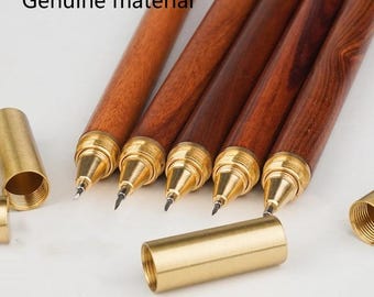 Puede incluir: Un conjunto de instrumentos de escritura con cuerpos de madera marrón oscuro y puntas y tapas de metal dorado. El texto Genuine material es visible en la esquina superior izquierda. Los bolígrafos presentan secciones roscadas.