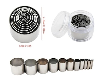 Puede incluir: Un juego de 12 cortadores circulares de metal plateado de diámetros variables, encajados en un recipiente de plástico transparente. La altura de cada pieza es de 2,5 cm. El conjunto se muestra tanto encajado como alineado por tamaño.