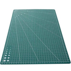 K&ouml;nnte beinhalten: Eine gr&uuml;ne Schneidematte mit wei&szlig;en Gitterlinien und Ma&szlig;angaben. Die Matte hat diagonale Linien und Zahlen entlang der Kanten, mit Messungen bis zu 109 cm. Ideal f&uuml;r Bastel- und N&auml;hprojekte.