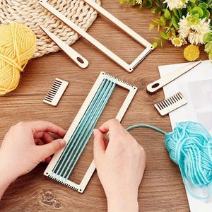 May include: A wooden weaving loom kit with light blue yarn being woven. The kit includes a rectangular frame, a comb, and a needle-like tool. Yellow and blue yarn balls are also visible.