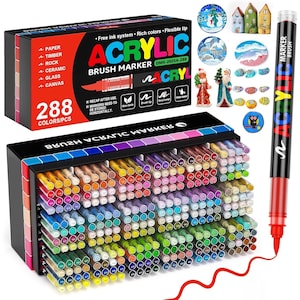 Op de afbeelding: Een set van 288 acryl brush markers in een zwarte opbergkoffer. De markers zijn in rijen gerangschikt en tonen een breed spectrum aan kleuren. Een rode marker met de tekst "ACRYLIC BRUSH MARKER" wordt getoond. De doos geeft de materialen aan: papier, hout, steen, keramiek, glas en canvas.
