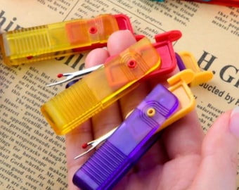 Puede incluir: Un conjunto de descosedores de plástico translúcido en colores amarillo, naranja, rojo y morado. Cada herramienta cuenta con una tapa protectora deslizante con una zona de agarre texturizada y una hoja metálica con punta de seguridad roja.