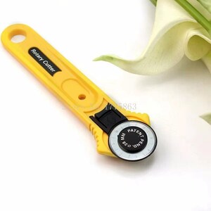 May include: Yellow rotary cutter with a black blade guard. The handle has the words "Rotary Cutter" printed on it. The blade is marked with "28 MM" and "Patent Pend."