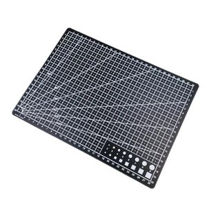 K&ouml;nnte beinhalten: Eine schwarze Schneidematte mit wei&szlig;en Gitterlinien, Winkelmarkierungen und Ma&szlig;angaben. Die Matte enth&auml;lt ein Lineal entlang der Kanten und verschiedene Formen und Gr&ouml;&szlig;en zum Schneiden. Die Ma&szlig;e sind in Zentimetern.