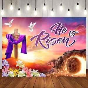 May include: A backdrop featuring a wooden cross draped with a purple cloth, two white doves, and the words "He is Risen" in purple script. The background depicts a sunrise over a mountainous landscape with a glowing tomb and flowers.